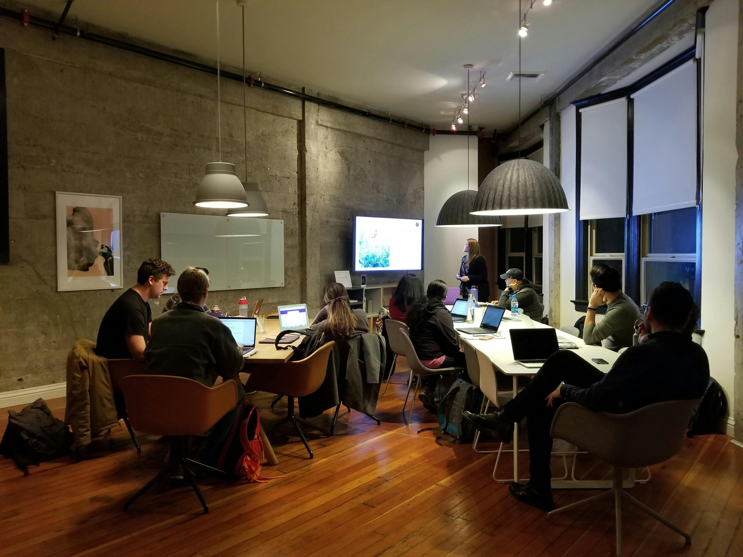 Home 4 Diverse team collaborating in a modern office setting with laptops and presentation screen. - Devcart Solutions
